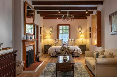 a living room with a bed and a fireplace at L'Auberge Chanteclair in Franschhoek