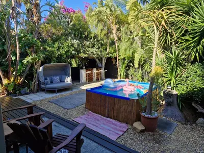 a patio with a table and a chair in a yard at Spacious home in Cape Towns Blouberg area in Cape Town