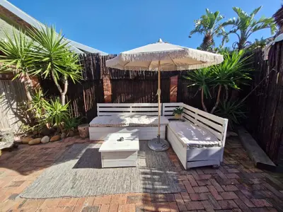 a patio with an umbrella and a bench and a table at Apartment with garden in Cape Town
