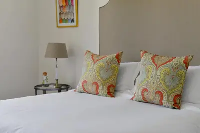 a bedroom with a white bed with two pillows at Fransvliet Guest House in Franschhoek