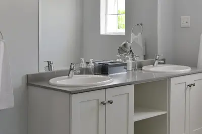 a white bathroom with two sinks and a mirror at Fransvliet Guest House in Franschhoek