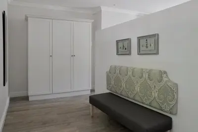 a white living room with a bench and a cabinet at Fransvliet Guest House in Franschhoek
