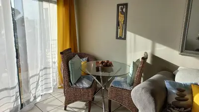a room with a glass table and chairs and a couch at Nautica Strand in Cape Town