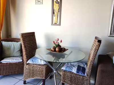 a table with two chairs and a bowl of fruit on it at Nautica Strand in Cape Town