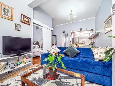 a living room with a blue couch and a tv at Cosy Victorian Style Full Apartment in Cape Town