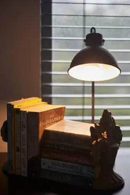 a stack of books sitting on a table with a lamp at Rondebosch Central in Cape Town