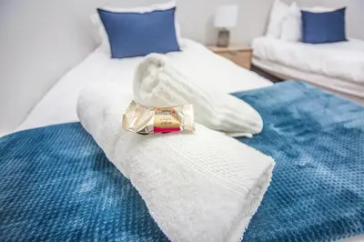 two beds with white sheets and a bag of food on them at @Villa de Vie holiday apartment in Cape Town