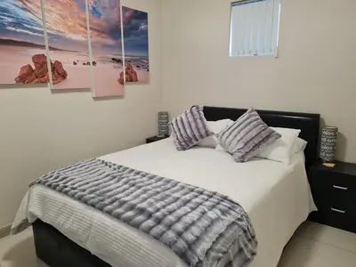 a bedroom with a bed with four paintings on the wall at Hermanus Beach Club UNIT 74 in Hermanus