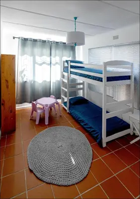 a room with two bunk beds and a rug at SeaCrest Cottage in Hermanus