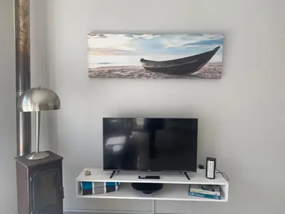 a living room with a tv and a boat on the wall at OysterCatcher Self-Catering Accommodation Strand in Cape Town