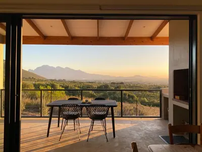 a table and chairs on a balcony with a view at Sneeukop Mountain Cottage in Paarl