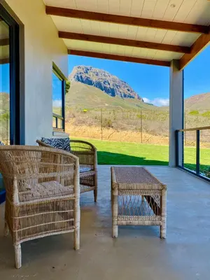 a porch with two chairs and a table and a mountain at Sneeukop Mountain Cottage in Paarl