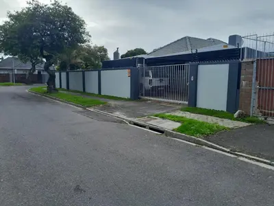 an empty street with a fence and a house at Magnolia Cottage in Cape Town