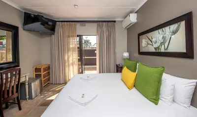 a bedroom with a white bed with yellow and green pillows at Excellent Guest House in Bellville