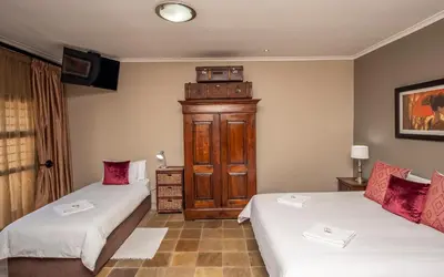 a room with two beds and a television at Excellent Guest House in Bellville