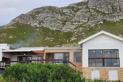 a house with a mountain in the background at Jock's Bay View in Bettyʼs Bay