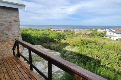 a wooden balcony with a view of the ocean at Jock's Bay View in Bettyʼs Bay