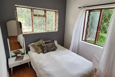 a small bedroom with a bed and a window at Jock's Bay View in Bettyʼs Bay