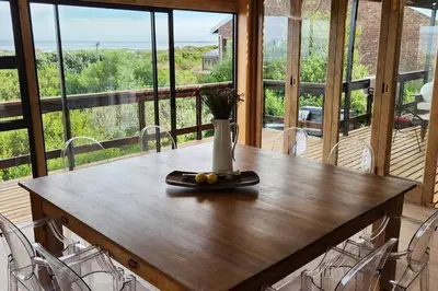 a wooden table with a vase on top of it at Jock's Bay View in Bettyʼs Bay