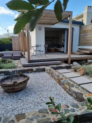 a backyard with a stone walkway and a wooden deck at Quaint Cottage in Hermanus