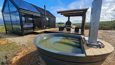 a hot tub in front of a glass house at Little Acre Luxury Pods in Tulbagh