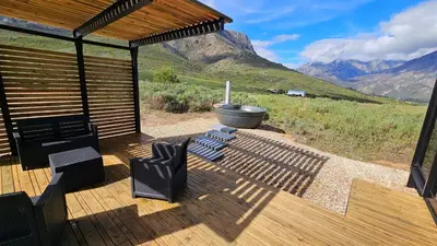 a wooden deck with chairs and a boat in a field at Little Acre Luxury Pods in Tulbagh