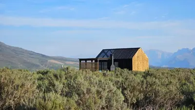 a small house on a hill with mountains in the background at Little Acre Luxury Pods in Tulbagh
