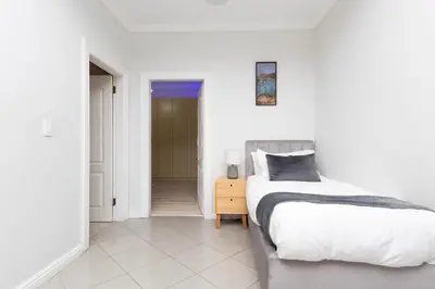 a white bedroom with a bed and a hallway at SERENA INN Apartment no5 in Cape Town
