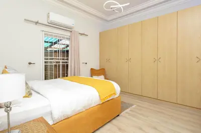a white bedroom with a bed and a window at SERENA INN Apartment no5 in Cape Town