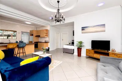 a living room with a blue couch and a tv at SERENA INN Apartment no5 in Cape Town