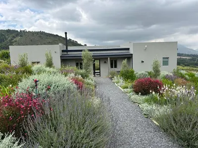 a white house with a garden of flowers at Windon vineyard farmhouse in Stellenbosch