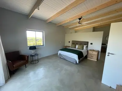 a bedroom with a bed and a chair and a window at Windon vineyard farmhouse in Stellenbosch