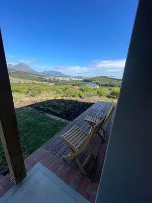 a wooden bench sitting on a porch with a view at Windon vineyard farmhouse in Stellenbosch