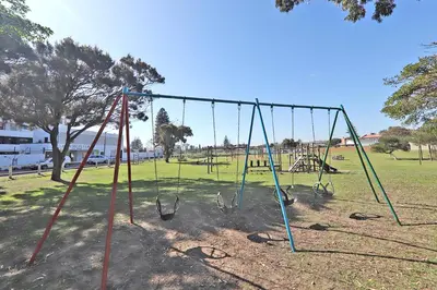 an empty playground with swings in a park at 002 Burmeister on Park- 2 minute walk from the beach in Cape Town