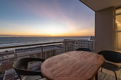 a table and chairs on a balcony with a view of the ocean at Stylish Sunlit Ocean View Oasis! in Cape Town