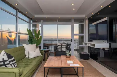 a living room with a green couch and a table at Stylish Sunlit Ocean View Oasis! in Cape Town