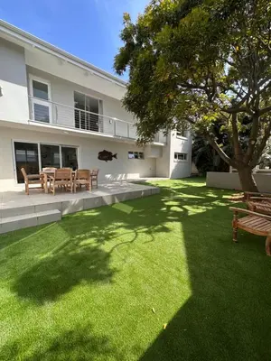 a yard with benches and a tree in front of a building at Ocean Pearl Hermanus - 5 Bedrooms in Hermanus