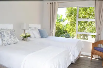 two beds in a white bedroom with a window at Ocean Pearl Hermanus - 5 Bedrooms in Hermanus