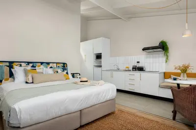 a bedroom with a large bed and a kitchen at Neighbourgood Franschhoek in Franschhoek