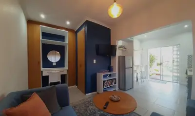 a living room with a blue couch and a table at Birdsong Cottage in Cape Town