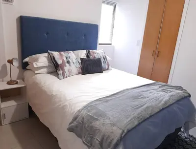a bed with a blue headboard in a bedroom at Birdsong Cottage in Cape Town
