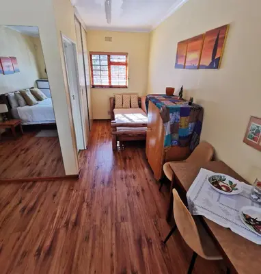 a living room with wood floors and a room with a couch at Somerset Grace Double en-suit in Somerset West