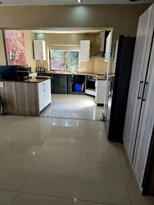 a large kitchen with white appliances and a large room at Bikini Beach Manor in Gordonʼs Bay