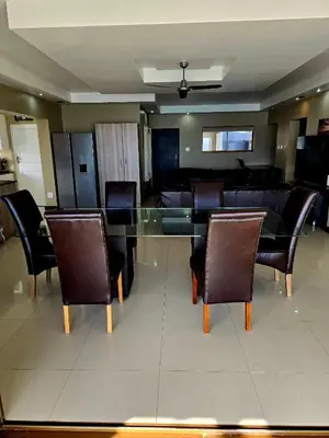 a dining room with a glass table and chairs at Bikini Beach Manor in Gordonʼs Bay