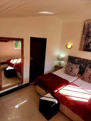 a bedroom with two beds and a mirror at Bikini Beach Manor in Gordonʼs Bay