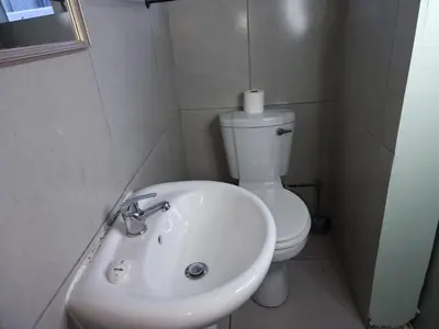 a white bathroom with a toilet and a sink at Ojong's Guesthouse Kraaifontein - Eikendel in Cape Town
