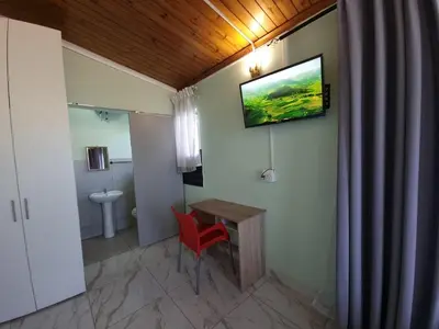 a bathroom with a red chair and a television on the wall at Ojong's Guesthouse Kraaifontein - Eikendel in Cape Town