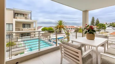 a balcony with a table and chairs and a pool at The W-Collection Esplanade Hermanus in Hermanus