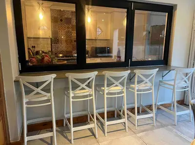 a kitchen with a bar with four white stools at 7de Hemel Paarl in Paarl