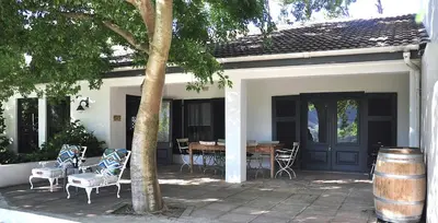 a house with a patio with a table and chairs at Blueberry Hill Cottages in Franschhoek